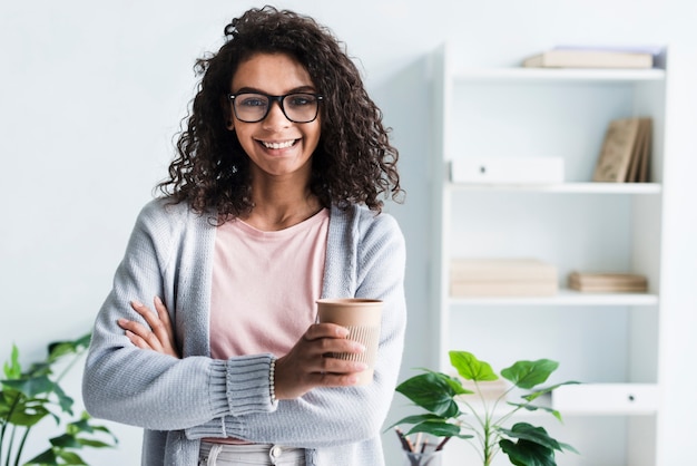 Beautiful young female with paper cup in office