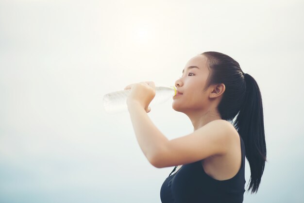 Красивая молодая женщина фитнес женщина питьевой воды после выполнения упражнения