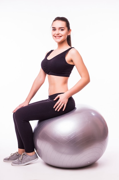 Beautiful young fitness woman with gym ball exercising, isolated on white background