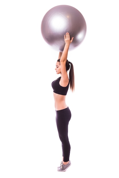 Beautiful young fitness woman with gym ball exercising, isolated on white background