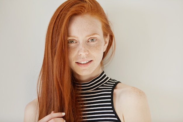 Beautiful young freckled green-eyed lady with long hairstyle posing indoors – Free Stock Photo