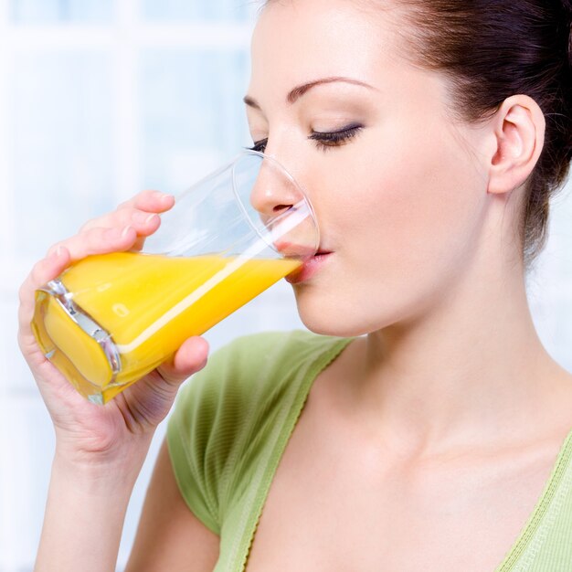 Beautiful young girl drinking fresh orange juice