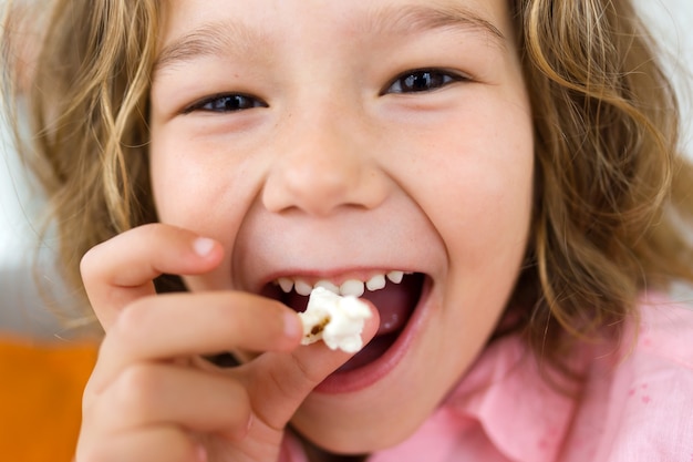 Free photo beautiful young girl eating popcorns at home.