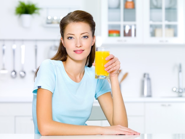 Beautiful young girl hold a glass of fresh orange juice