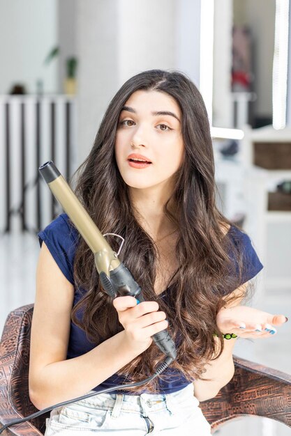 A beautiful young girl holding hair dryer and looking at the camera High quality photo