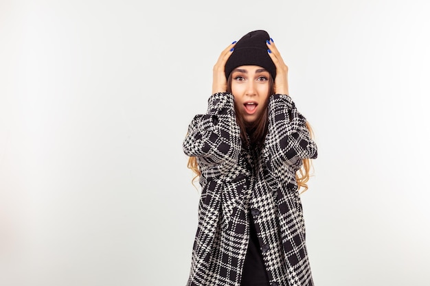 Beautiful young girl holding her hands to her head and looking at the camera with open mouth