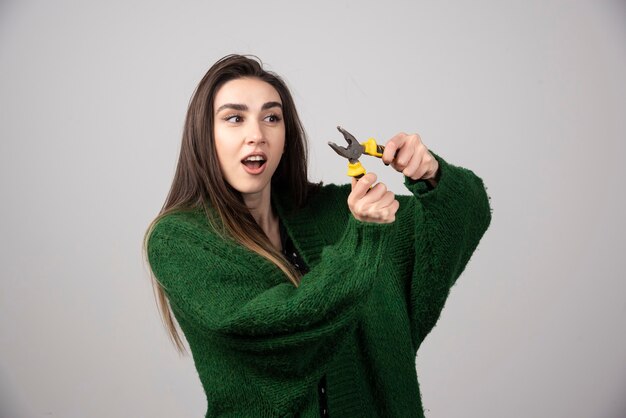 A beautiful young girl holding pliers in her hands.