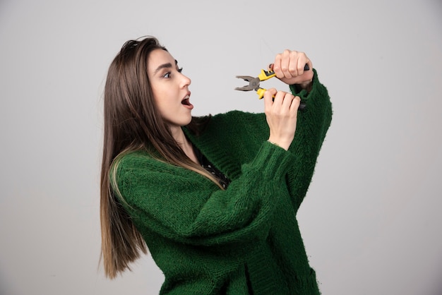 A beautiful young girl holding pliers in her hands.