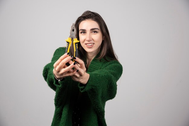 A beautiful young girl holding pliers in her hands.