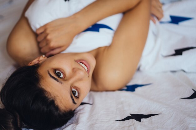 Beautiful young girl is sleeping. She is waking up and smiling. Medium shot