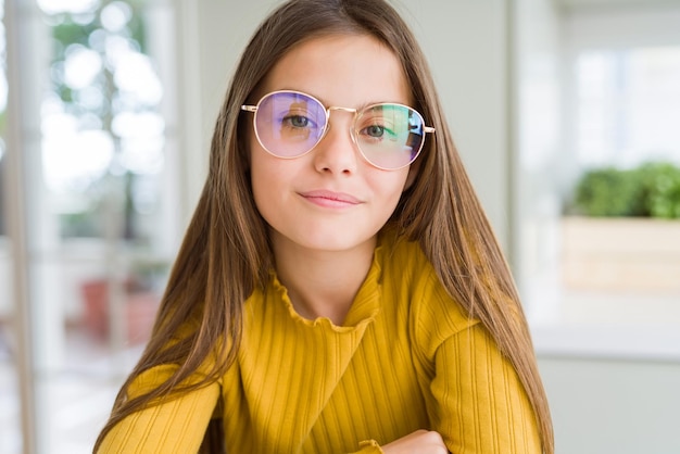 Beautiful young girl kid wearing glasses Relaxed with serious expression on face Simple and natural with crossed arms
