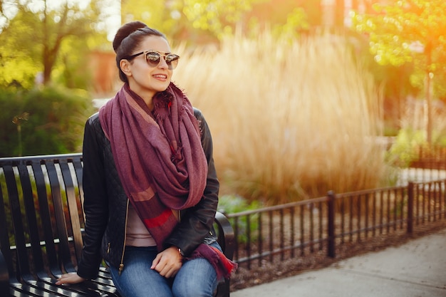 Free photo beautiful young girl in a leather jacket and scarf sitting on the streets of chicago