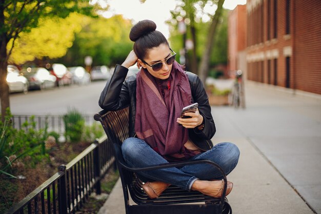 beautiful young girl in a leather jacket and scarf sitting on the streets of Chicago 