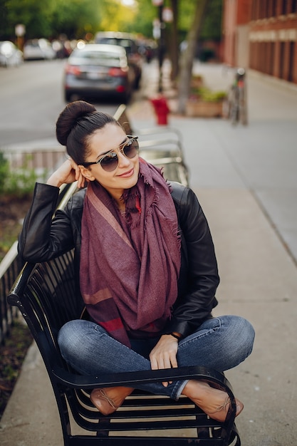 シカゴの通りに座っている革ジャケットとスカーフの美しい少女