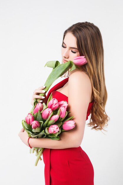 Beautiful young girl smelling pink tulips