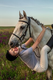 그녀의 말 드레싱 유니폼 경쟁에 아름 다운 젊은 여자 미소: 일몰에 야외 초상화. 동물, 사랑과 우정 개념을 돌보는 것.