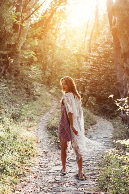 Beautiful, young girl walks at the foot of the mountain along