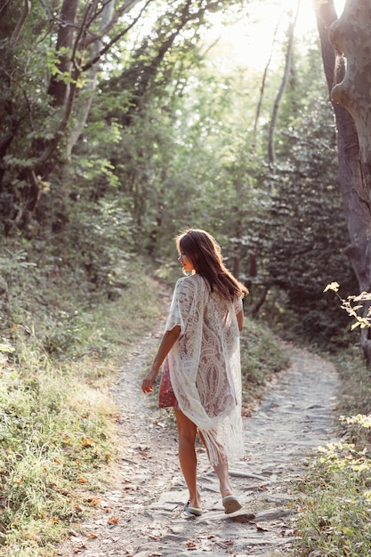 Beautiful, young girl walks at the foot of the mountain along