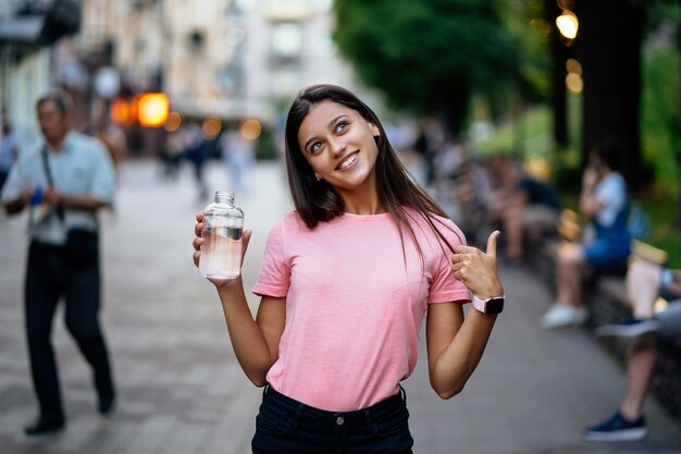Красивая молодая девушка с бутылкой воды на улице города