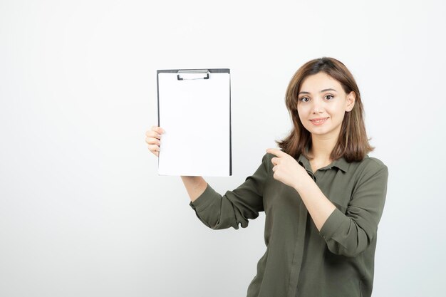 Beautiful young girl with clipboard standing and posing over white. High quality photo