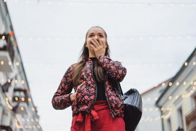 屋外でポーズを取る長い髪と美しい若い幸せなブルネットの女の子。ストリート写真、ポートレート、クローズアップ。