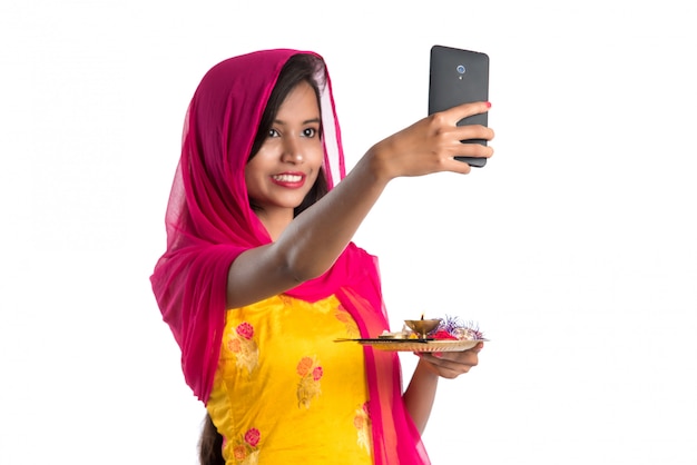 Красивая молодая счастливая девушка принимая selfie с пуджа тхали с помощью мобильного телефона или смартфона