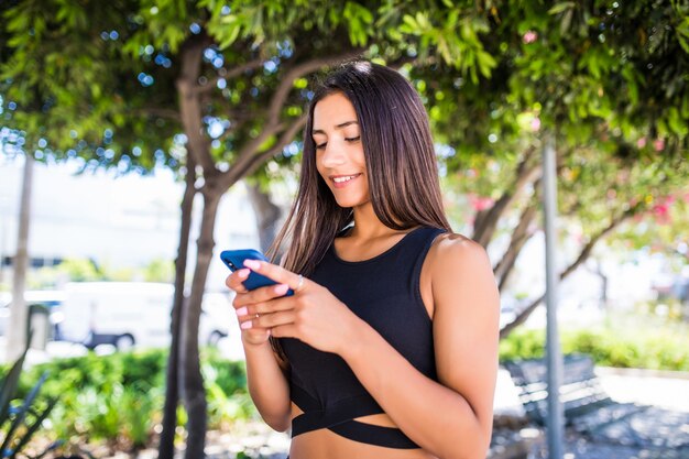 Красивая молодая счастливая латинская женщина отправляет СМС на мобильный телефон на улице города. Студент девушка идет и текстовые сообщения на мобильный телефон на открытом воздухе на улице города в зимнее время.