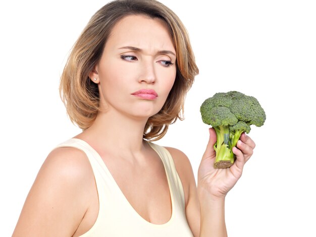 Beautiful young healthy woman holds broccoli isolated on white.