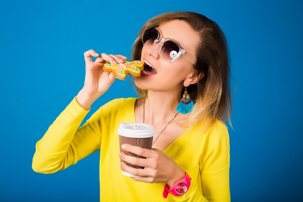 美しい若い流行に敏感な女性、クッキーを食べて、コーヒーを飲む