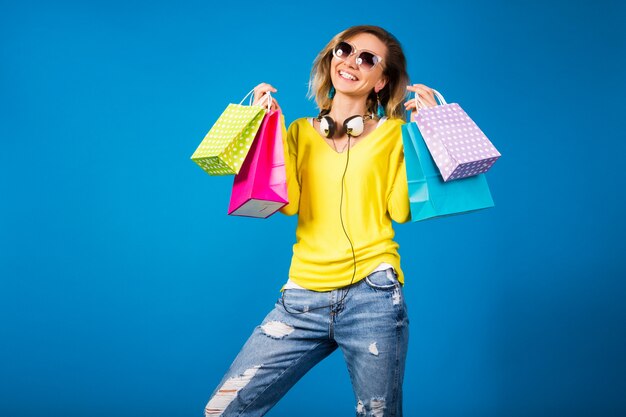 Beautiful young hipster woman, holding colorful paper shopping bags