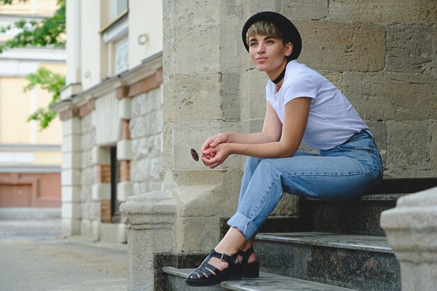 Beautiful young hipster woman posing sitting on stairs