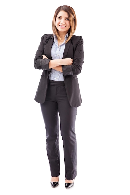 Beautiful young Hispanic salesperson wearing a suit and standing against a white background