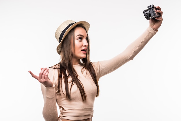 Beautiful young lady in bright t-shirt and hat makes selfie on retrocamera isolated on white