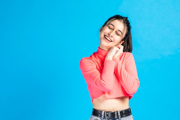 Beautiful young lady close her eyes and smiling on blue background