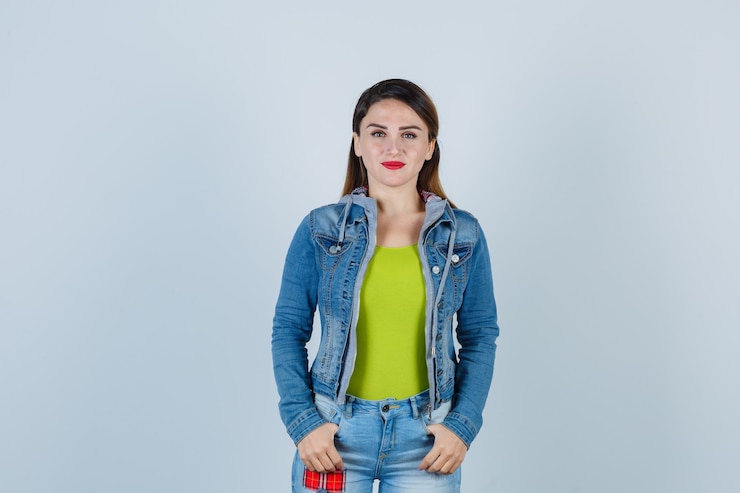 मुफ़्त फोटो beautiful young lady keeping thumbs in pockets in denim outfit and looking cheerful , front view.