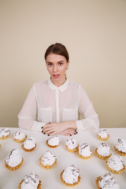 Beautiful young lady posing while sitting near cupcake