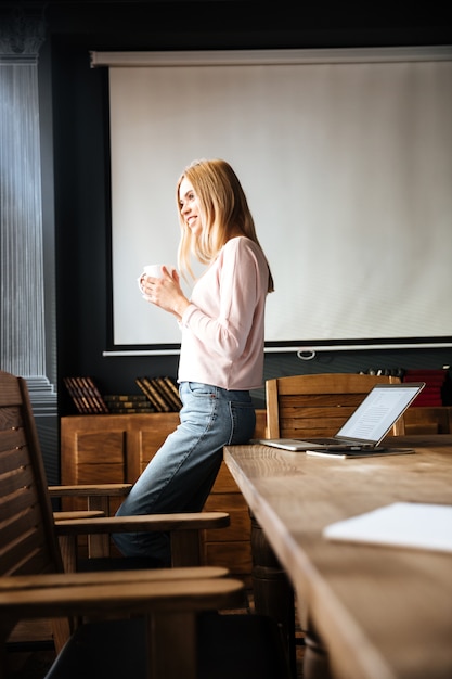 Beautiful young lady standing in cafe work with laptop.