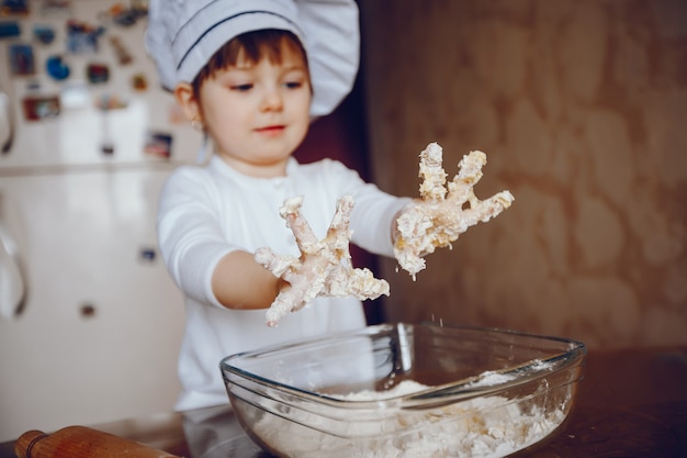 Free photo a beautiful young little daughter is cooking in the kitchen at home