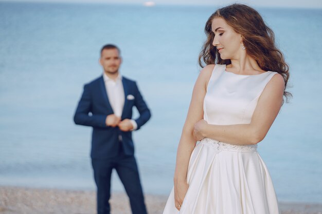 彼女の若い夫とビーチで白いドレスの美しい若い長髪の花嫁