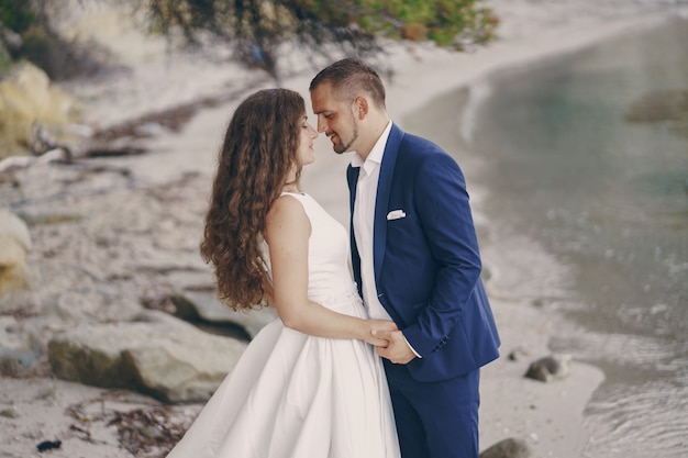 해변에서 그녀의 젊은 남편과 하얀 드레스를 입고 아름다운 젊은 긴 머리 신부