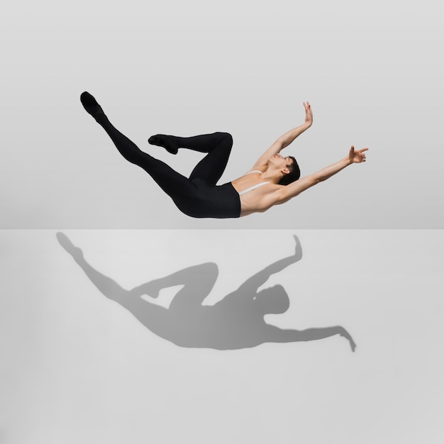 Free photo beautiful young male athlete practicing on white studio with shadows in jump, air flying