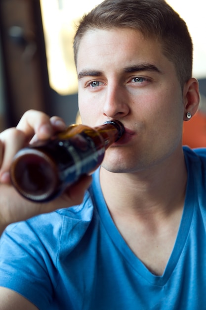 バーでビールを飲む美しい若い男。