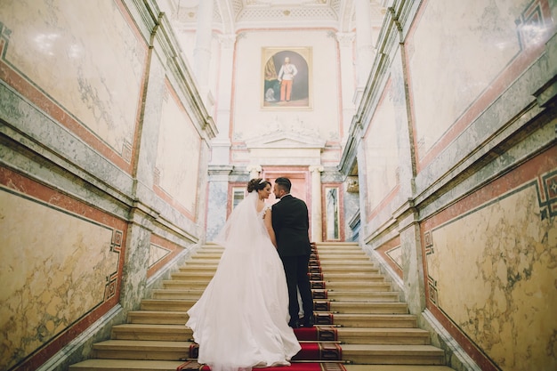 A beautiful young man wearing a black suit standing along with his bride