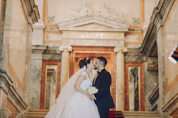 Free photo a beautiful young man wearing a black suit standing along with his bride