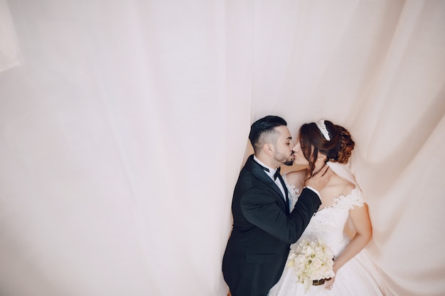 Free photo a beautiful young man wearing a black suit standing along with his bride