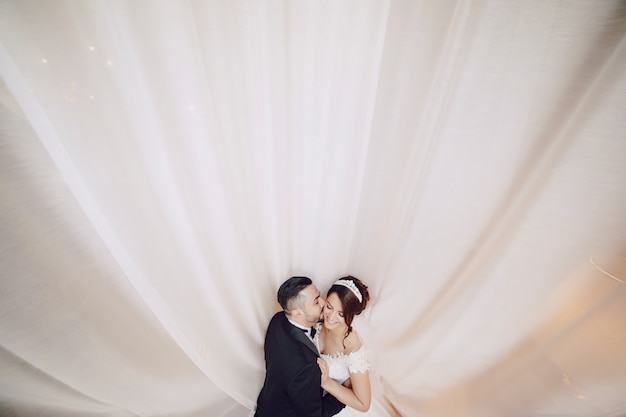 A beautiful young man wearing a black suit standing along with his bride