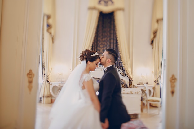 A beautiful young man wearing a black suit standing along with his bride