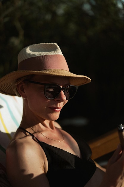 красивая молодая женщина средних лет в соломенной шляпе и купальнике. Лето, пляж, отдых.