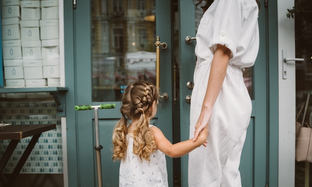 Beautiful young mother and cute little daughter walking down the street