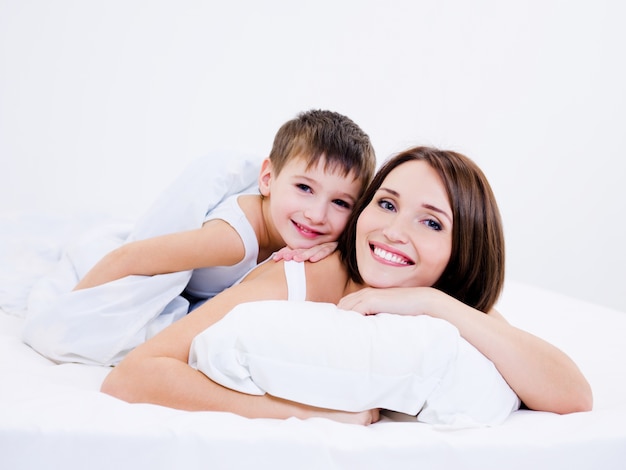 Красивая молодая мать и сын, лежа на кровати